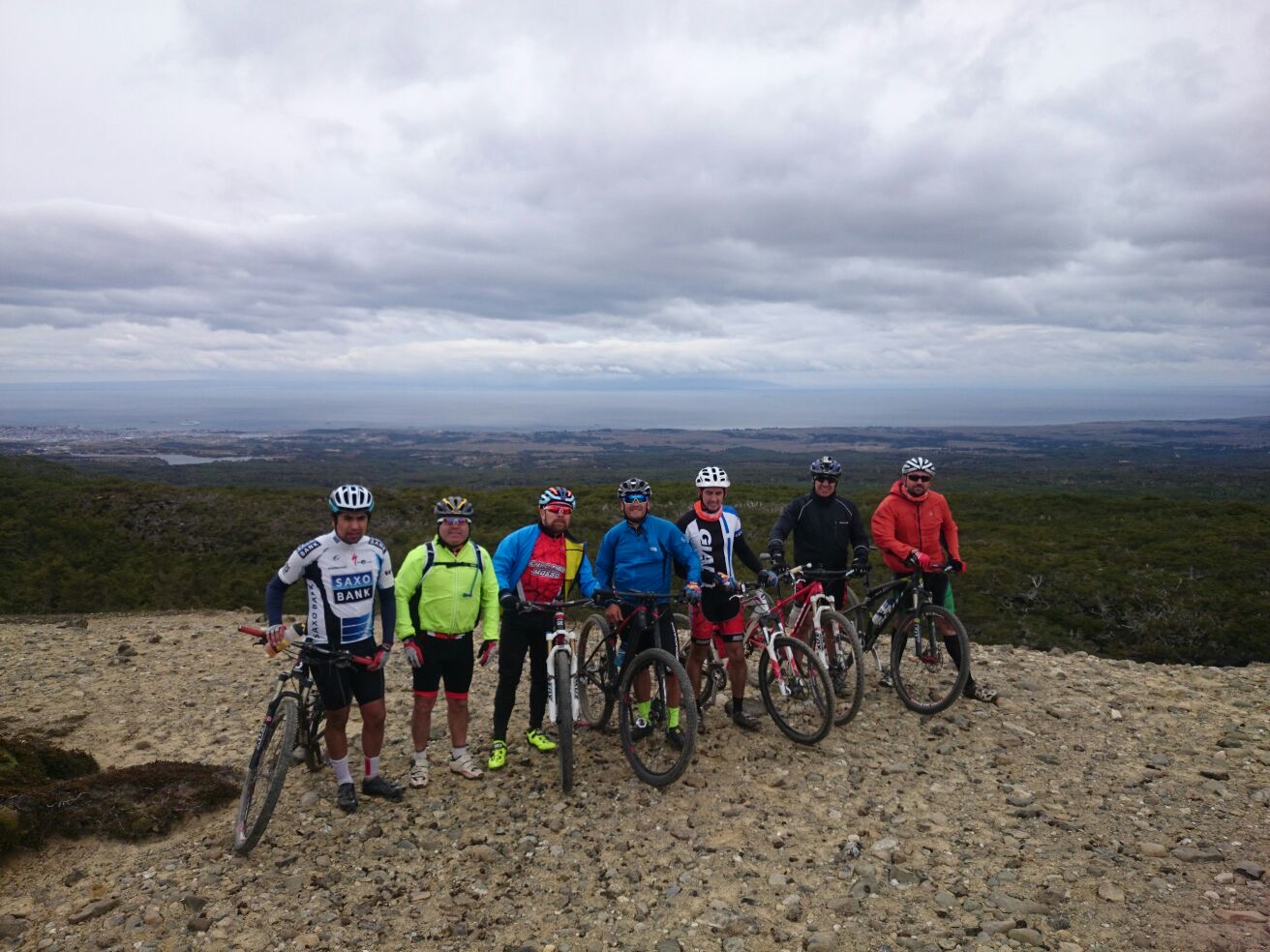 Integrantes del club con sus bicicletas en lo alto de un cerro, bajo un cielo nublado de Magallanes